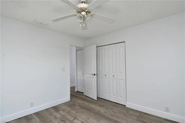 Guest bedroom featuring wood-style tile floors, ceiling fan, a textured ceiling and a closet
