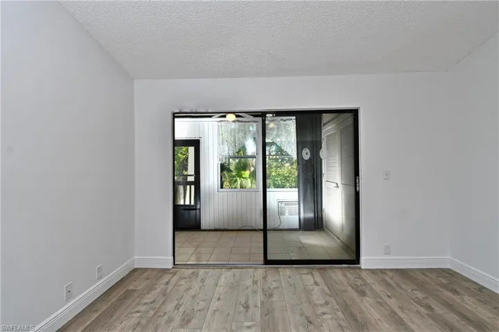 Living Room with sliders to rear lanai featuring tiled / wood-style floors and a textured ceiling