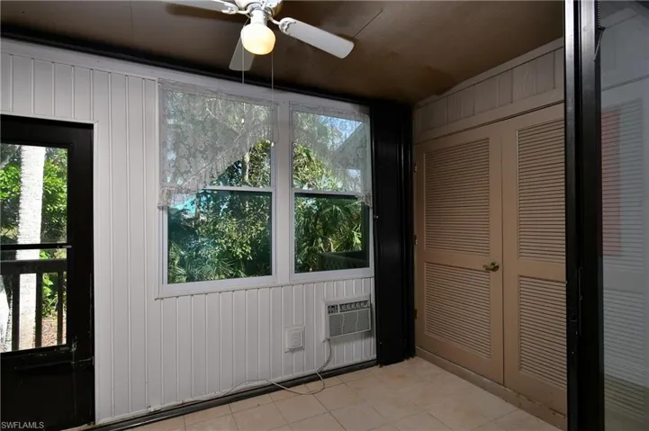 Entryway featuring wooden walls, ceiling fan, and light tile patterned flooring