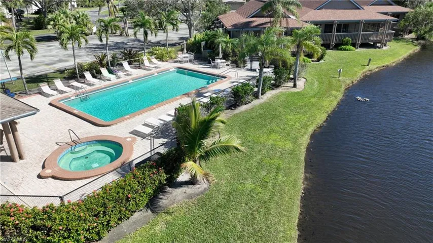 View of swimming pool featuring a lawn, a water view and a large lounging deck.