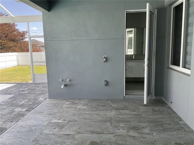 The property features an outdoor screened enclosure with a gray tiled patio and a paved section