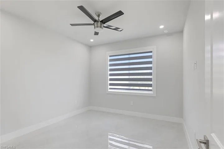 This room features light-colored walls and flooring, a ceiling fan, and recessed lighting