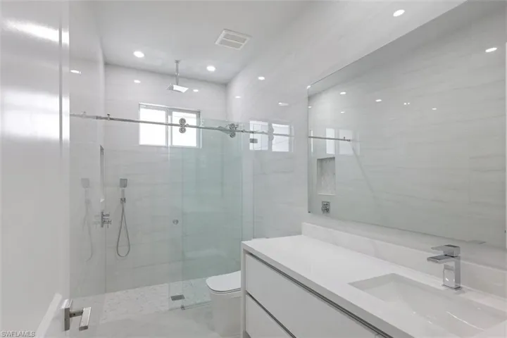 Bathroom featuring a spacious walk-in shower with a glass enclosure, a contemporary vanity with an integrated sink, and recessed lighting