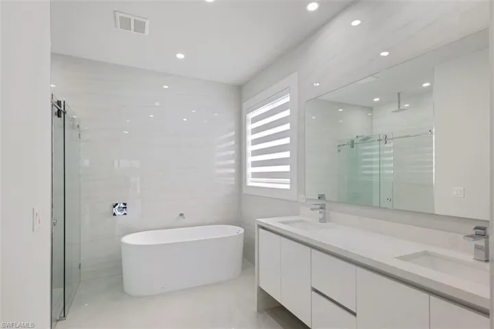 Spacious bathroom featuring a freestanding tub, glass-enclosed shower, dual vanity with undermount sinks, and a large mirror