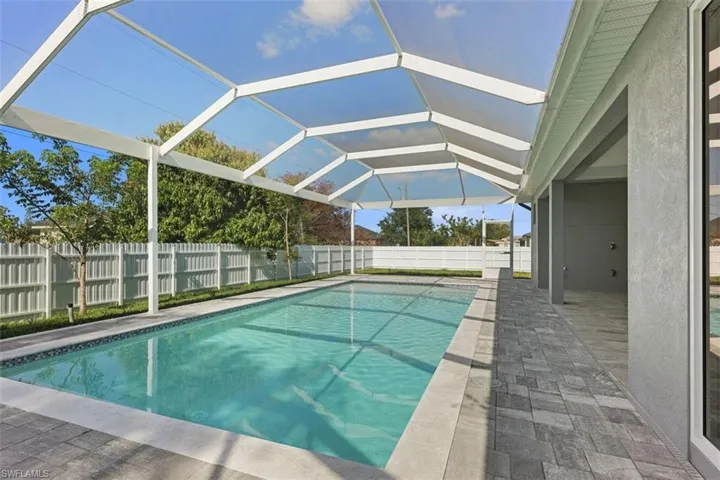 The property features a screened-in swimming pool with a paved deck, a perimeter fence, and ample space for outdoor enjoyment
