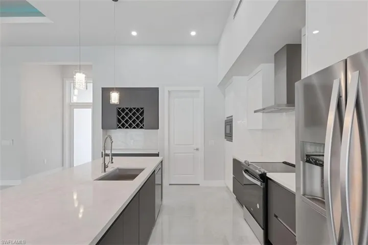 The kitchen features a spacious island with an integrated sink, sleek dark cabinetry, and stainless steel appliances including a refrigerator, oven, and range hood
