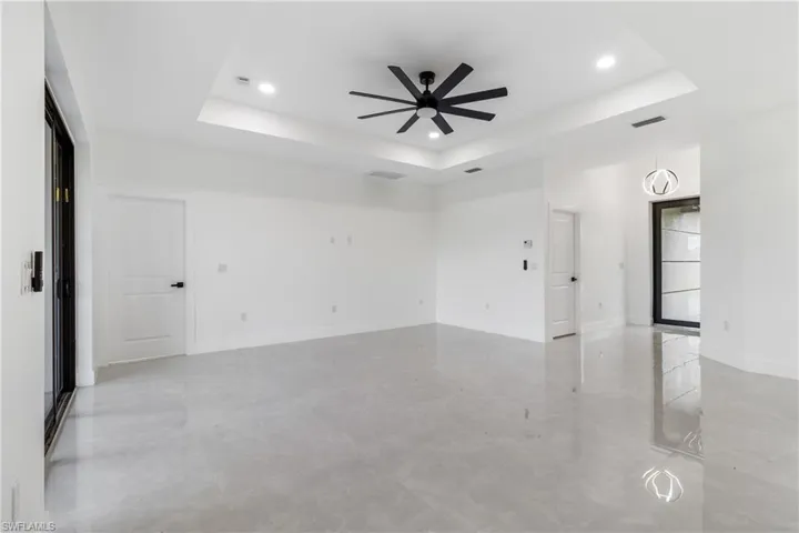 Spare room with a raised ceiling, recessed lighting, and ceiling fan