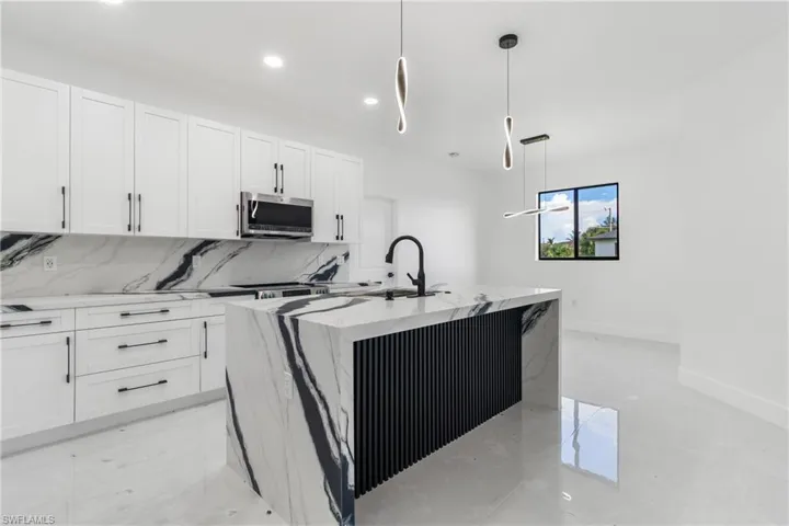 Kitchen with backsplash, white cabinetry, light stone counters, recessed lighting, and hanging light fixtures
