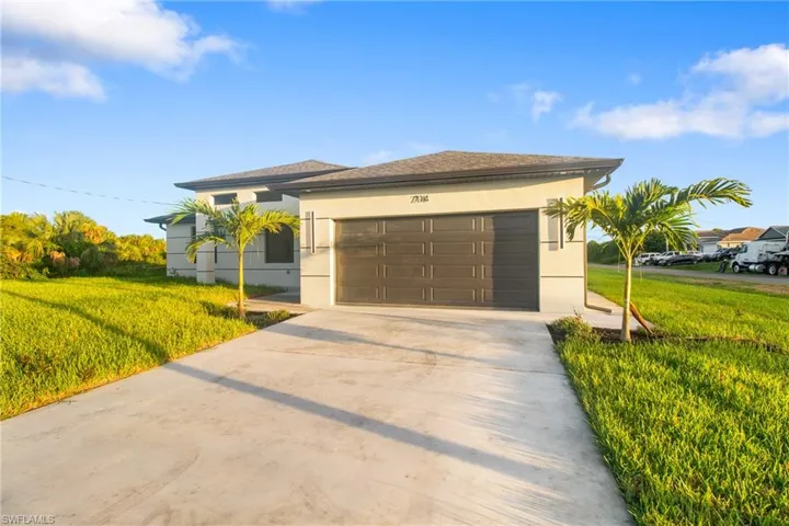 View of front of property with stucco siding, driveway, an attached garage, and a front yard