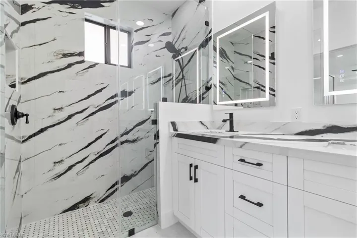Bathroom with vanity and a marble finish shower