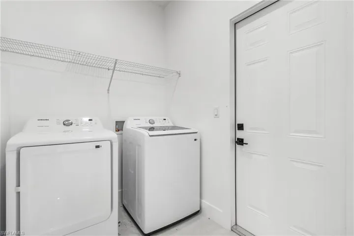 Washroom with washing machine and clothes dryer and baseboards