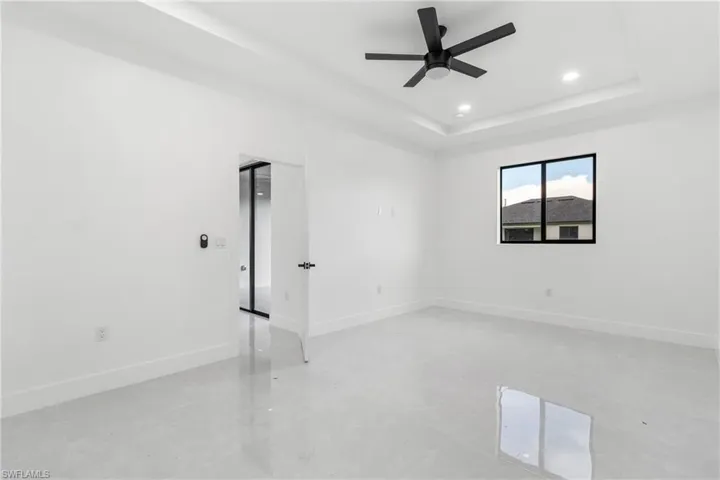 Unfurnished room featuring a tray ceiling, recessed lighting, and a ceiling fan