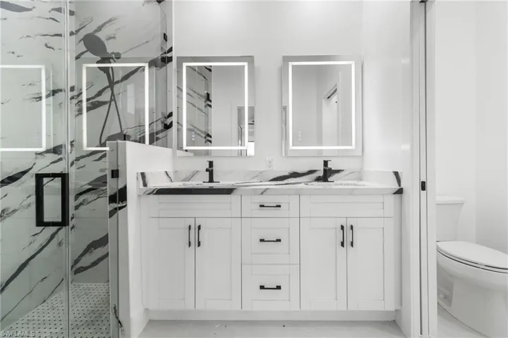 Full bath with a marble finish shower and double vanity