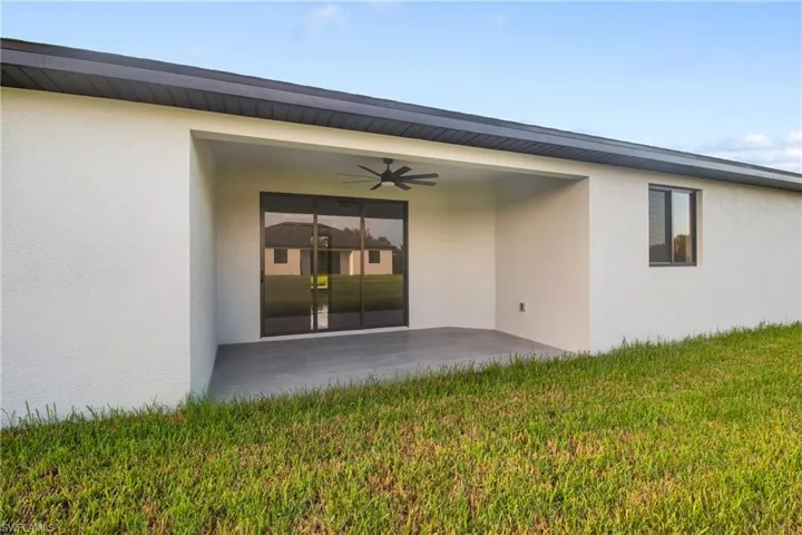 Rear view of house featuring a patio area, a ceiling fan, stucco siding, and a lawn