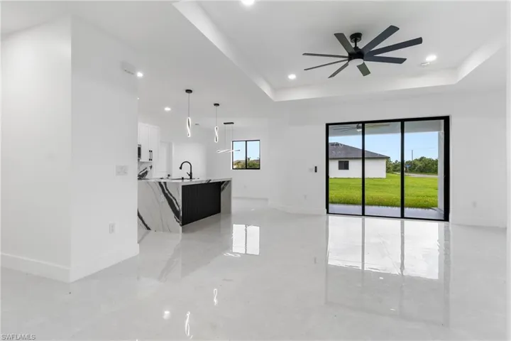 Unfurnished living room with a raised ceiling, recessed lighting, and a ceiling fan