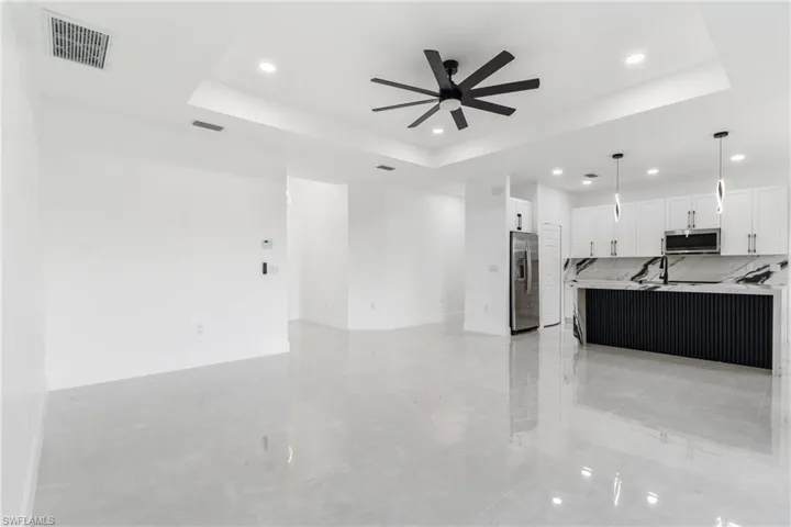 Unfurnished living room featuring a tray ceiling, recessed lighting, and ceiling fan