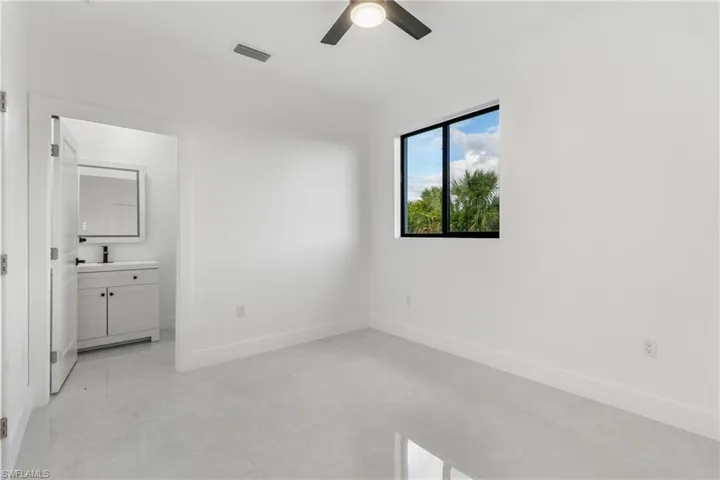 Unfurnished bedroom featuring ceiling fan, ensuite bathroom, and light tile patterned floors