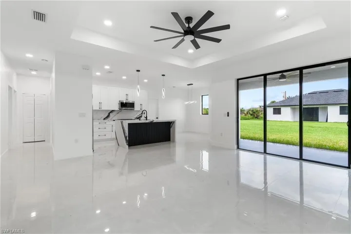 Unfurnished living room featuring a raised ceiling, recessed lighting, and a ceiling fan