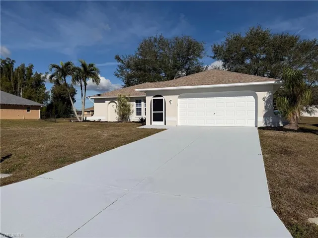 Ranch-style home featuring a front lawn, concrete driveway, stucco siding, and an attached garage