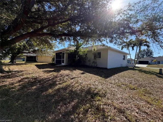 Rear view of property with stucco siding and a lawn
