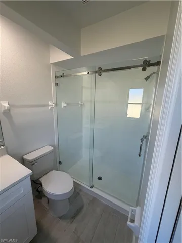 Full bath featuring a shower stall, light wood-type flooring, vanity, and a textured wall