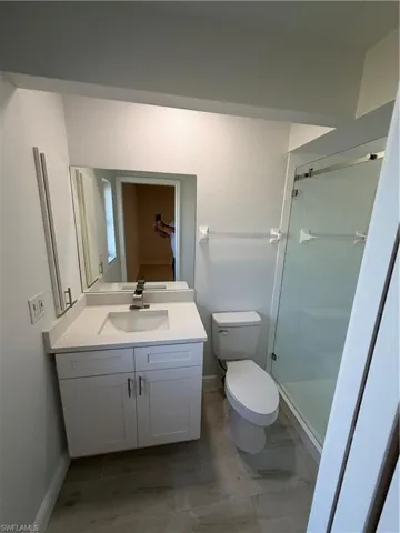 Full bath with vanity, a shower stall, and a textured wall