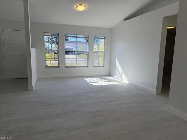 Unfurnished room featuring wood finish floors and lofted ceiling