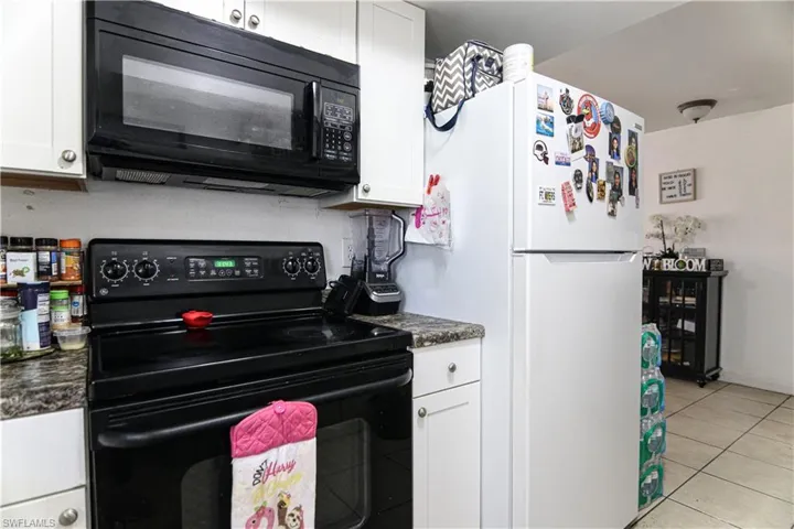 Kitchen featuring black appliances, dark countertops, and white cabinetry
