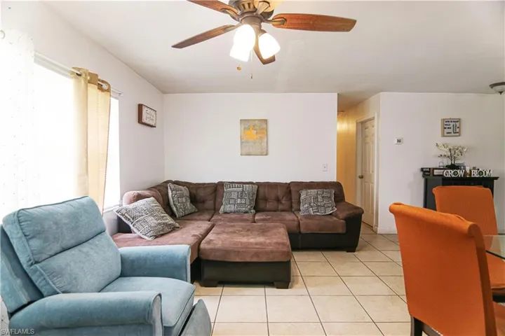Living area featuring light tile patterned flooring, ceiling fan, and healthy amount of natural light