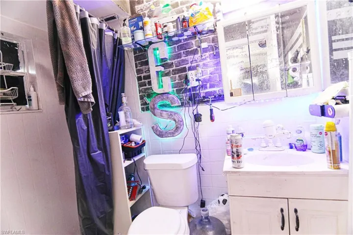 Bathroom featuring vanity, a shower with curtain, tile walls, and tasteful backsplash