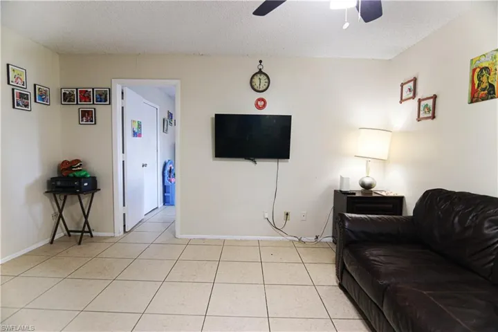 Living area featuring a ceiling fan, light tile patterned floors, and a textured ceiling