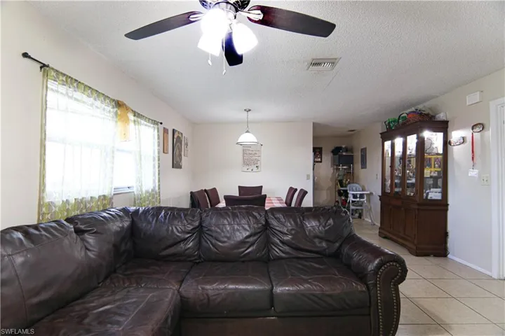 Living room featuring light tile patterned floors, ceiling fan, and a textured ceiling