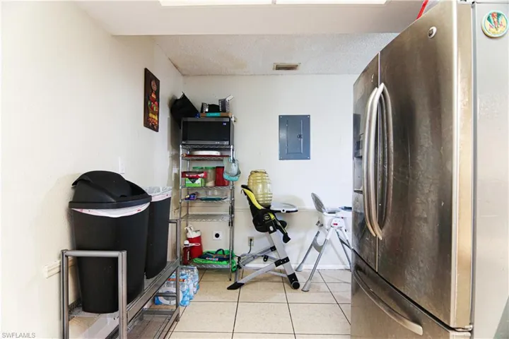 Workout room featuring electric panel and light tile patterned floors