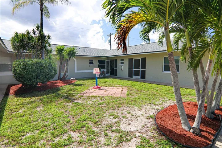 Back of house featuring stucco siding, a lawn, and a patio