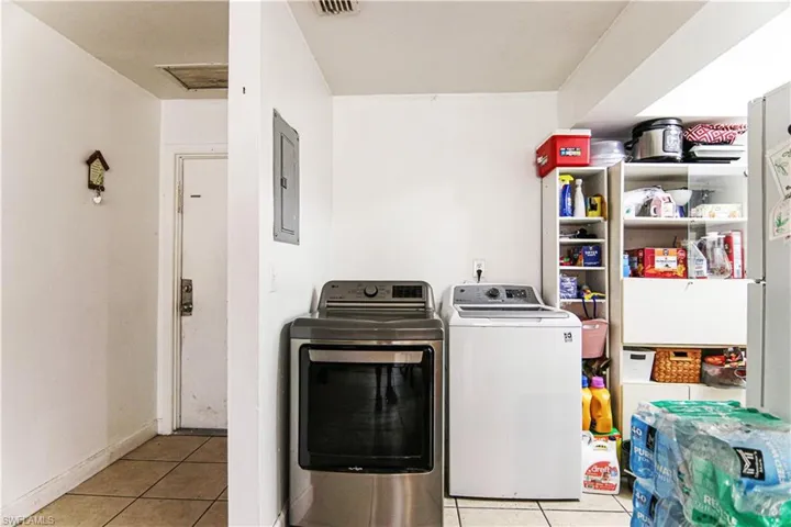 Laundry area featuring washer and dryer, tile patterned floors, and electric panel