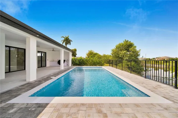 View of pool with ceiling fan, a water view, and a patio