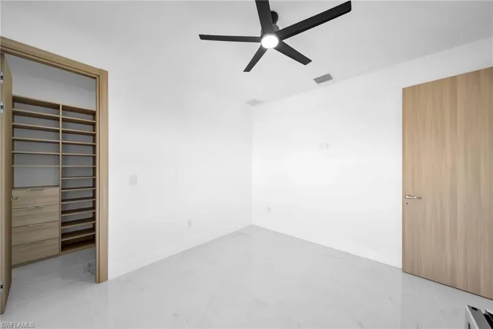 Empty room with light tile patterned flooring and ceiling fan