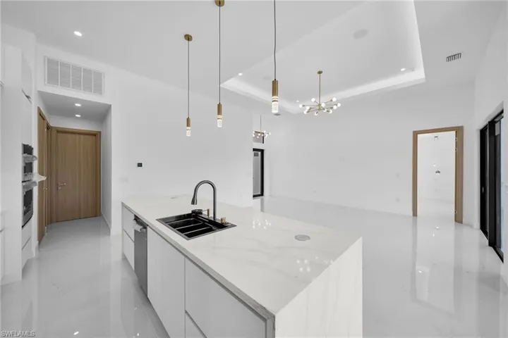 Kitchen featuring sink, pendant lighting, light tile patterned floors, a large island, and a tray ceiling