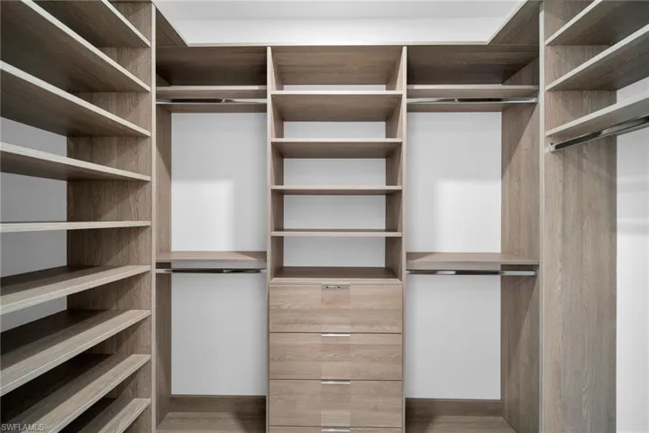 Walk in closet with dark hardwood / wood-style flooring