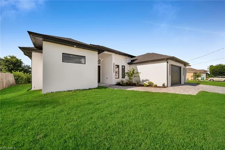 Rear view of property featuring a garage and a lawn