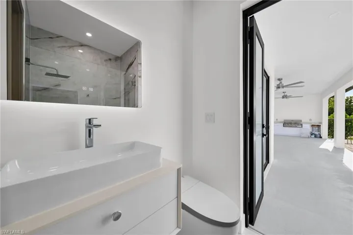Bathroom featuring walk in shower, toilet, vanity, and ceiling fan