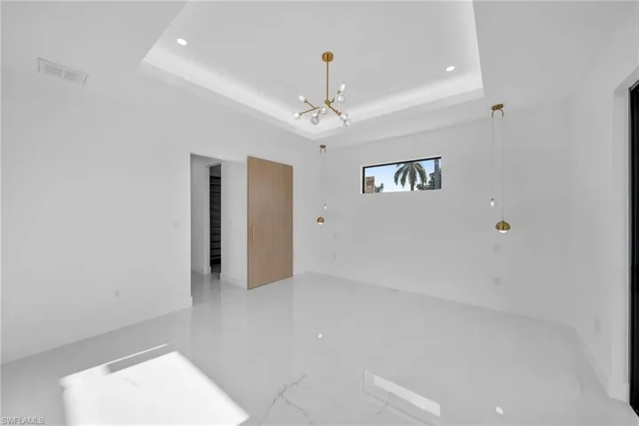 Tiled spare room with an inviting chandelier and a raised ceiling
