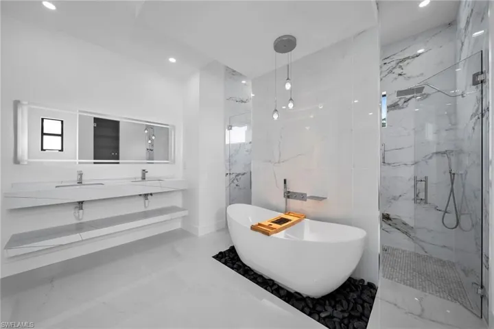 Bathroom with tile walls, shower with separate bathtub, tile patterned floors, and vanity