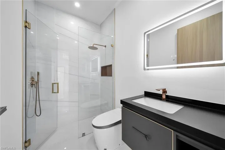 Bathroom with vanity, an enclosed shower, and toilet