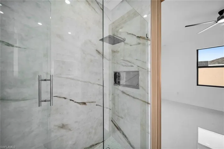 Bathroom featuring a shower with door and ceiling fan