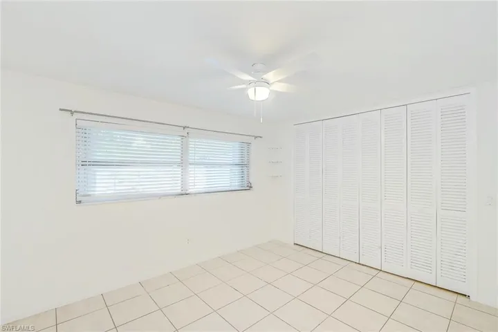Unfurnished bedroom with ceiling fan, light tile patterned flooring, and a closet