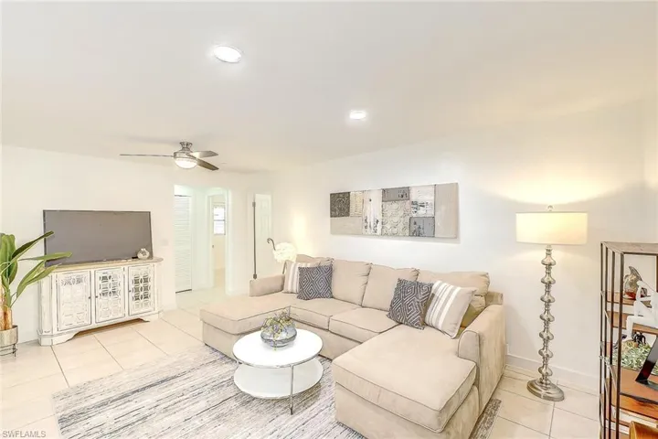Living room with ceiling fan and light tile patterned flooring