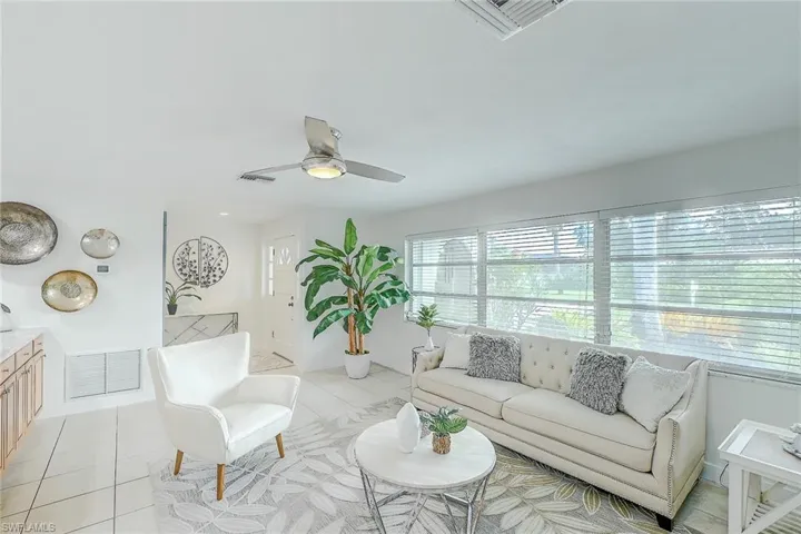 Living room with ceiling fan and light tile patterned flooring