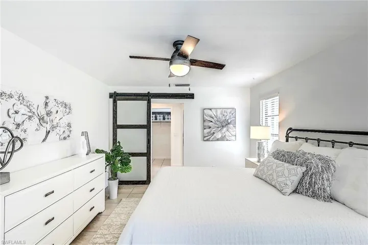 Tiled bedroom with a barn door and ceiling fan