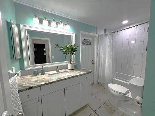 Full bathroom featuring vanity, toilet, shower / bath combination with curtain, and tile patterned flooring